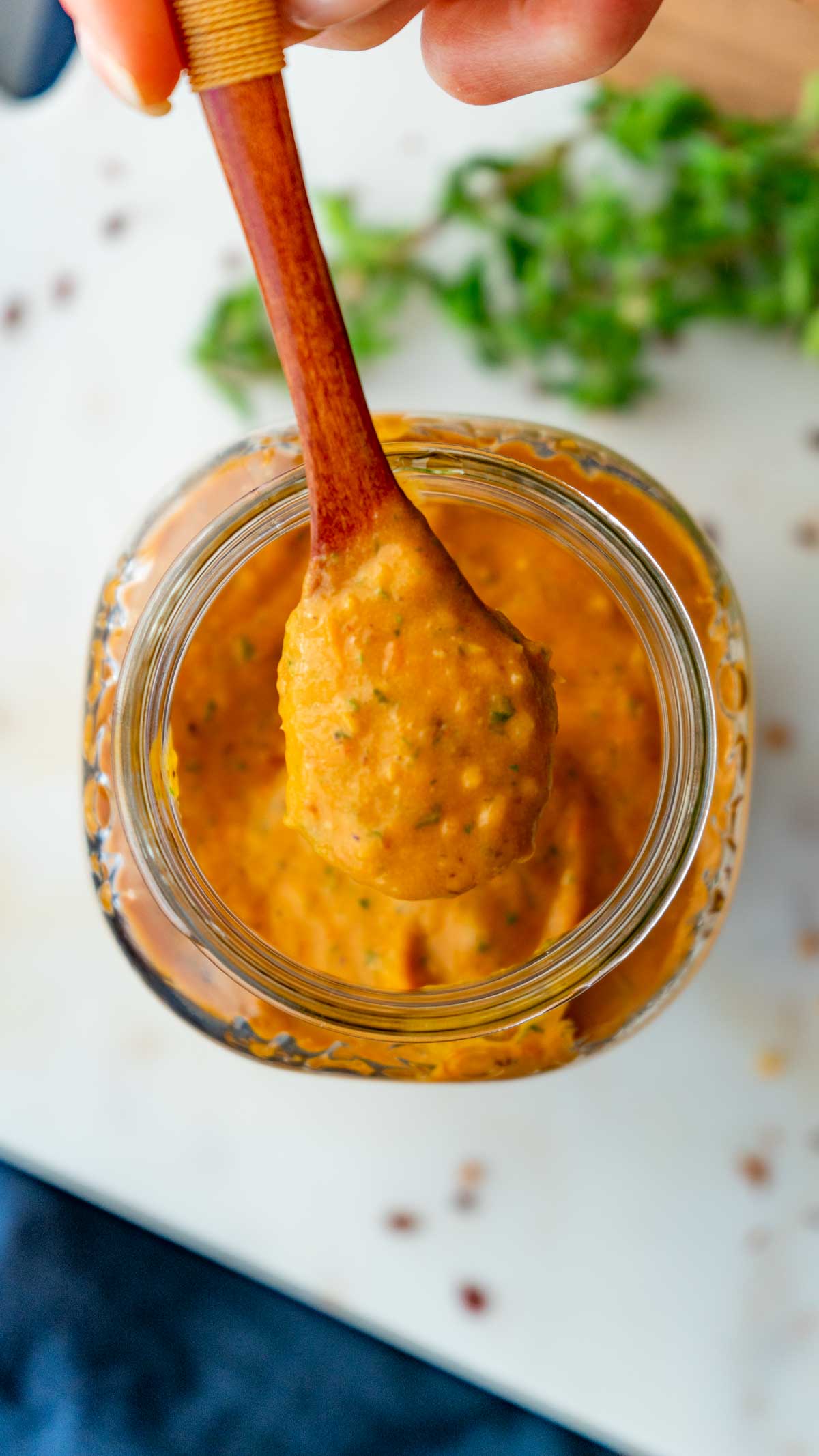 Roasted cherry tomatoes un a jar with a small wood spoon