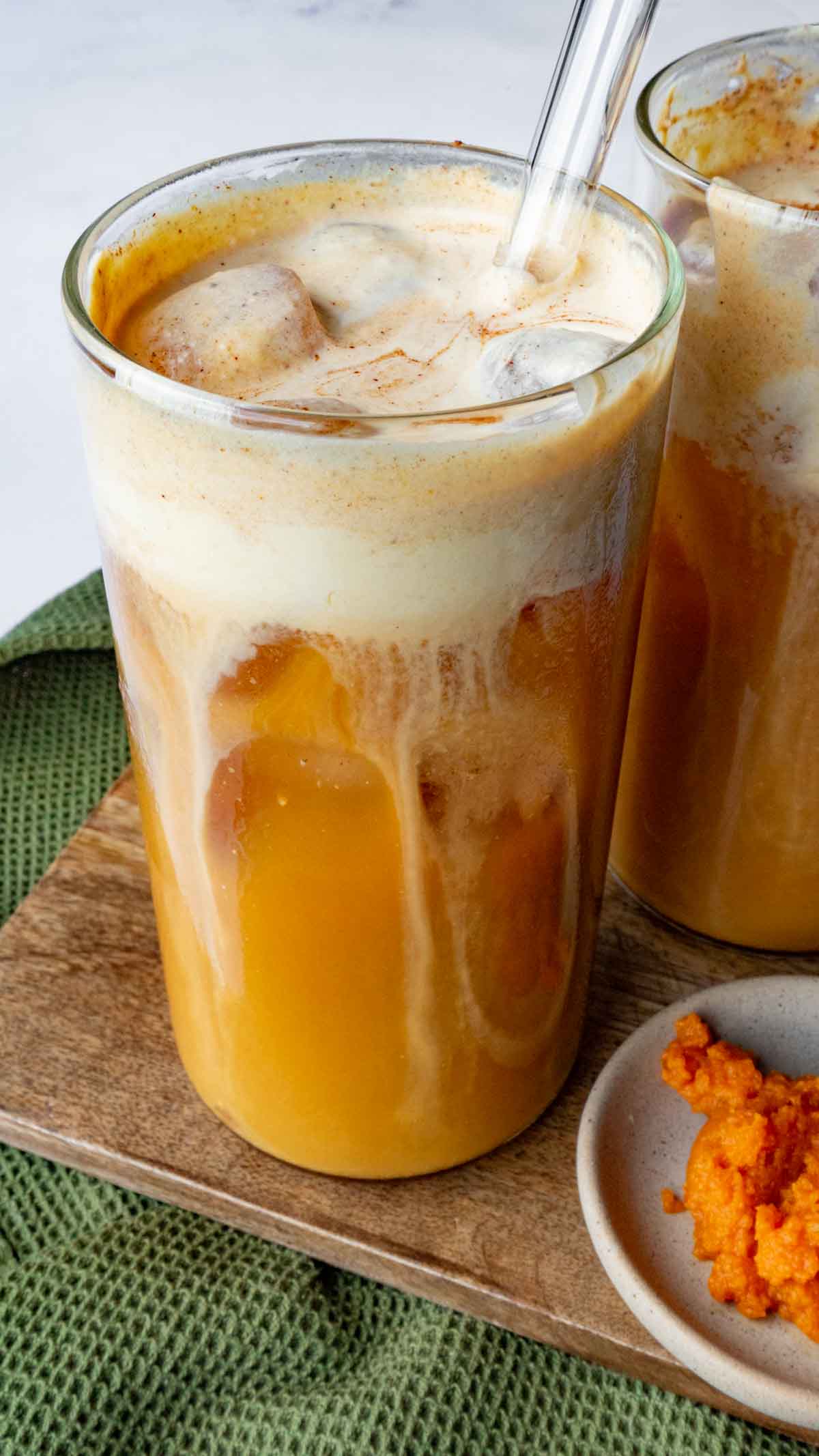 Cold brew with Pumpkin Cold Foam and ice on a wood cutting board