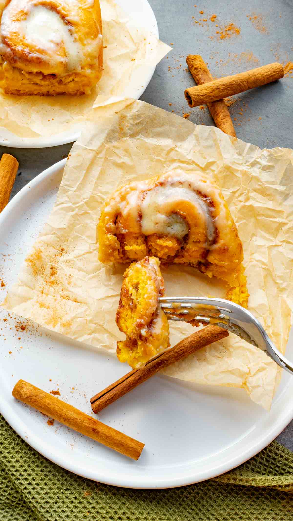 pumpkin cinnamon roll being cut into with a fork on a white plate 