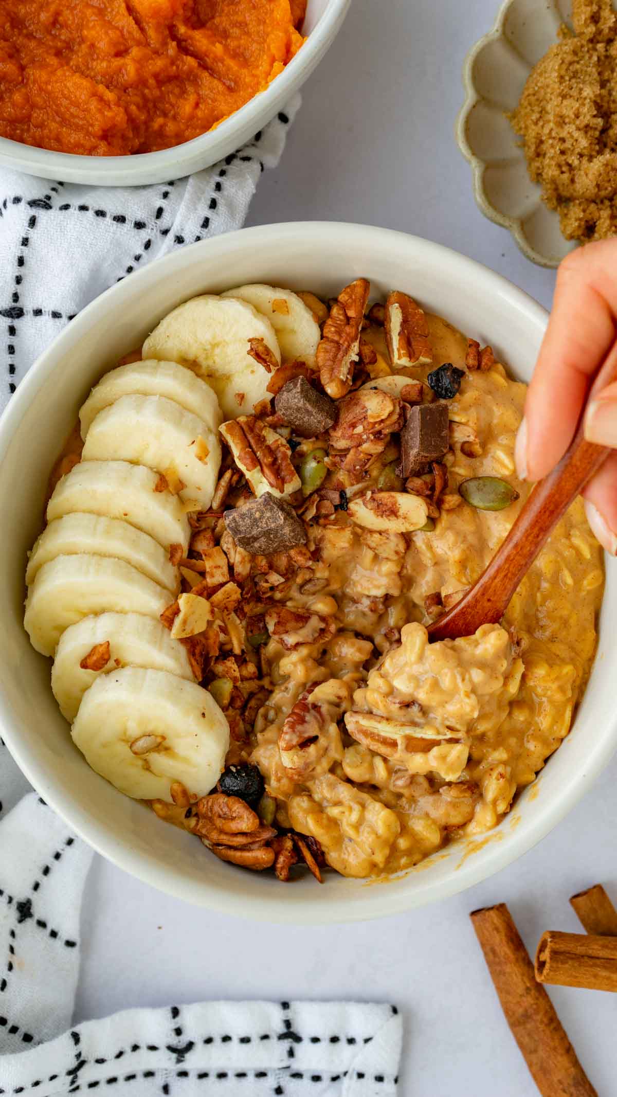 Pumpkin Pie Oatmeal in a white bowl with granola and banana slices