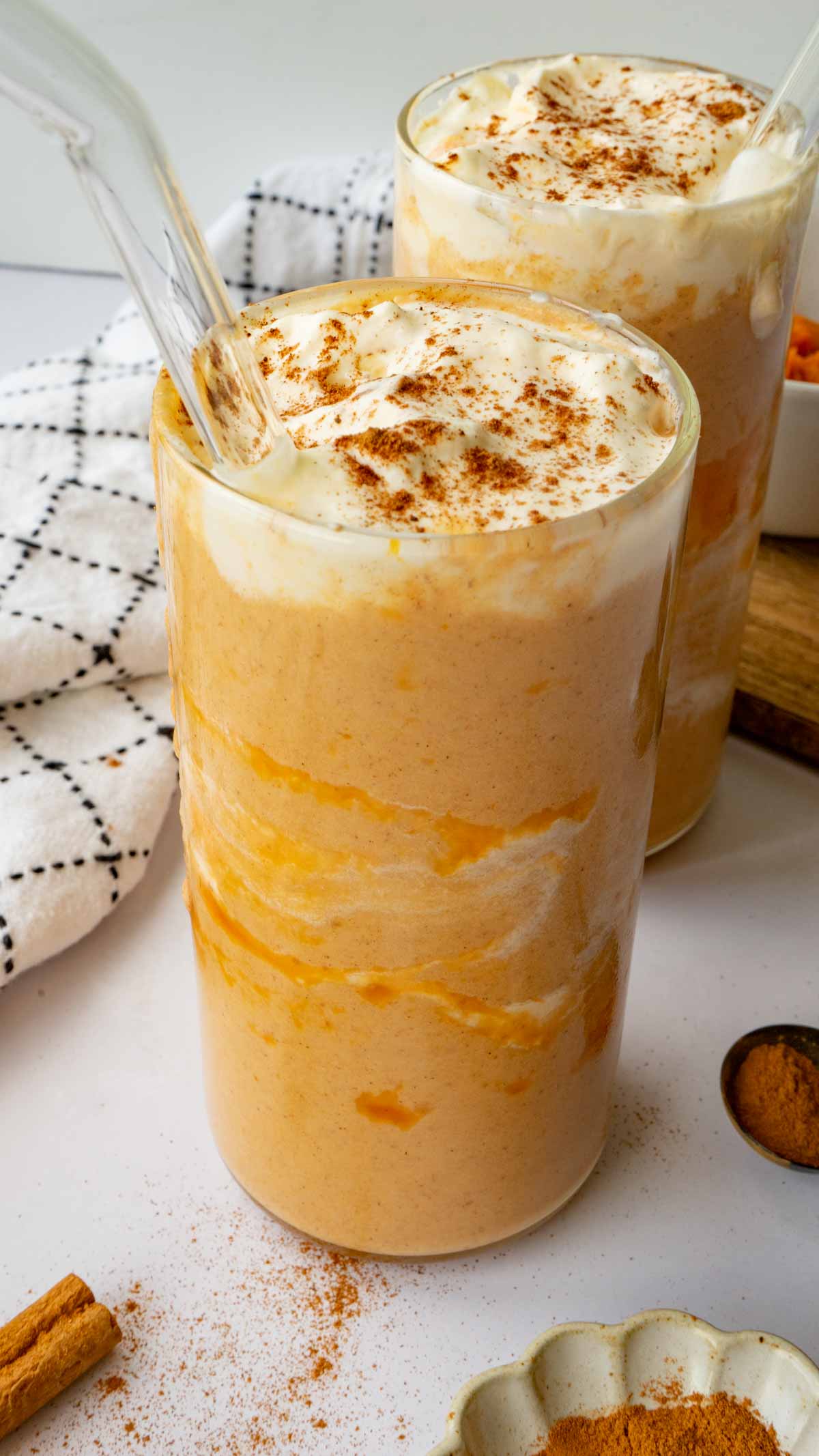 Pumpkin pie smoothie in a glass cup with whip cream and cinnamon on top