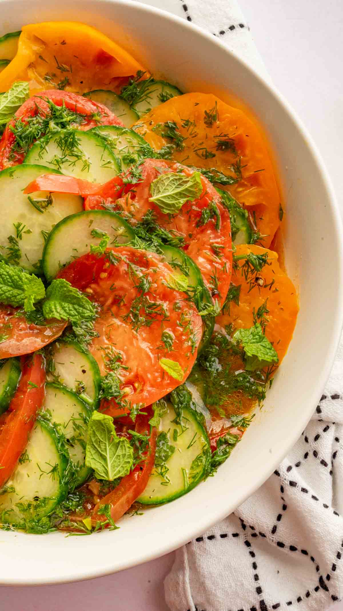 Heirloom Tomato and Cucumber Salad in a white bowl over a white kitchen cloth